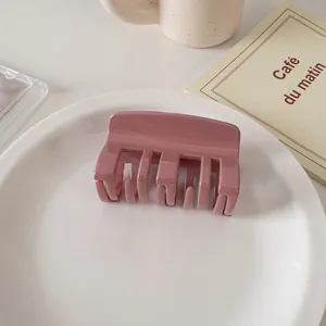 Detail of a glossy mauve square hair claw clip placed on a minimalist ceramic plate