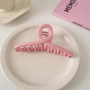 Detail einer gewellten rosa Haarklammer auf einer cremefarbenen Keramikplatte bei Licht