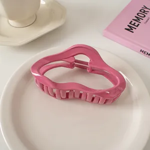 Detailaufnahme einer rosa gewellten Haarklammer auf einem Keramikteller im Wohnambiente