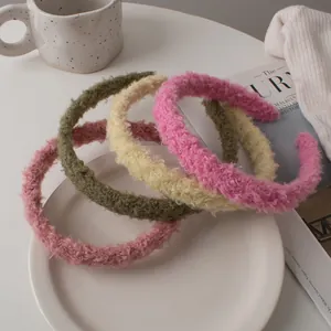 Detailed texture of pink, green and beige plush lamb wool headbands on a tray