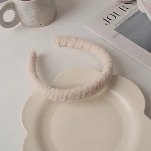 Détail du serre-tête en peluche crème sur plateau montrant la texture douce de la polaire