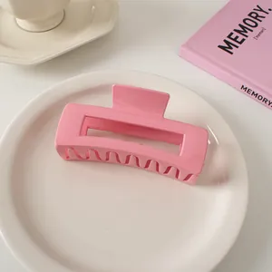 Detail einer großen glänzenden rosa rechteckigen Haarklammer auf weißem Keramikteller