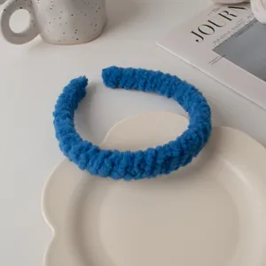 Détail d'un serre-tête bleu en peluche à texture douce posé dans un plateau céramique