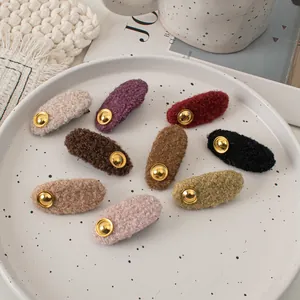 Close-up of wool hair clips in 8 candy colors with golden buttons on ceramic plate