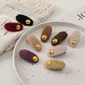 Detailed close-up of colorful wool felt oval hair clips with elegant gold metal buttons
