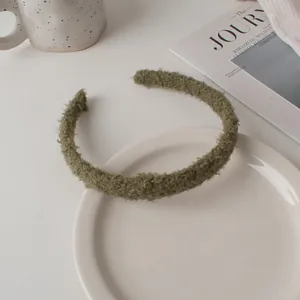 Detail of moss green sherpa fleece headband on a white ceramic plate with cozy decor