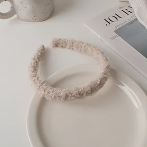 Detail shot of a soft plush beige headband on a tray with lifestyle props and a magazine