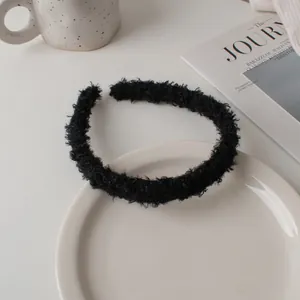 Close-up of black fuzzy lamb wool headband texture on a minimalist ceramic plate display