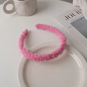 Close-up of pink faux lamb wool headband with soft plush texture on white decorative tray