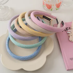 Close-up of colorful macaron fabric headbands with handmade label in a ceramic tray