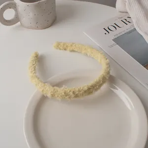 Detail of light yellow plush headband featuring soft fleece texture on a white plate