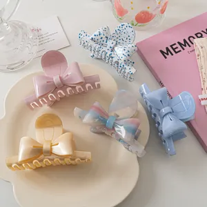 Détails de cinq pinces à cheveux en forme de nœud aux couleurs pastel sur une assiette blanche