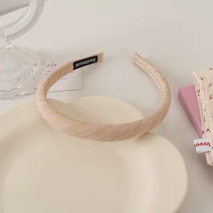 Detailed macro view of handmade light beige textured fabric headband with handmade label