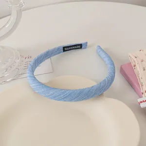 Detailed close-up of light blue fabric headband with handmade label on cream tray