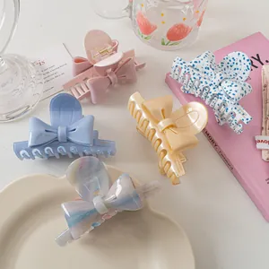 Détail de pinces à cheveux en forme de nœud, tons pastel rose, bleu et marbré