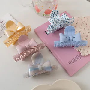 Gros plan de pinces à cheveux à nœuds pastel près d'un verre et de livres