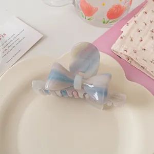 Détail macro d'une pince à cheveux nœud en acétate avec marbrure rose bleue et lettres dorées