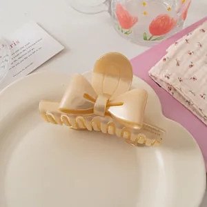 Détail de la pince à cheveux noeud crème avec inscription France Handmade sur plat blanc