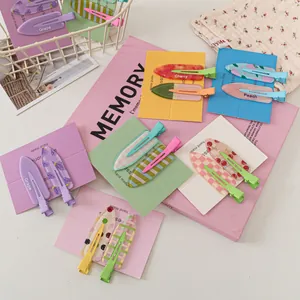 Flat lay of colorful fruit pattern hair clips with checkered and polka dot designs on card