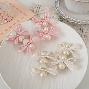 Detail view of pink and ivory silk bow hair clips with pearls on a decorative tray