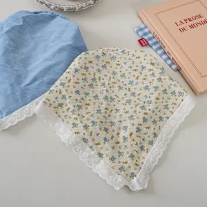 Detail eines floralen Spitzen-Haartuchs und blauen Bandanas im Set mit zwei Accessoires