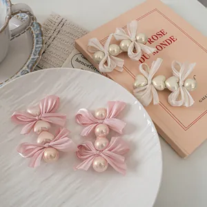 Elegant pink and cream ribbon bow hair clips set with pearls on a vintage tray