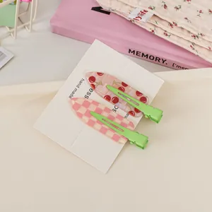 Close-up of seamless hair clips with cherry and pink checkerboard patterns on white card