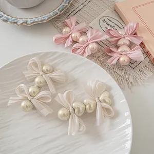 Pink and beige bow hair clips set with pearls and hearts on a ceramic plate