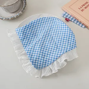 Detail eines blau-weiß karierten Stoff-Stirnbands mit breitem, weißem Plissee-Spitzenrand