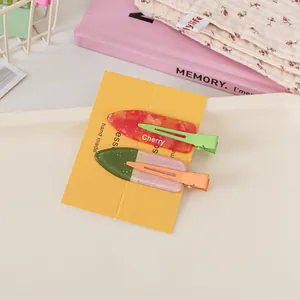 Detail of two resin juice-themed hair clips with Cherry lettering and glitter finish