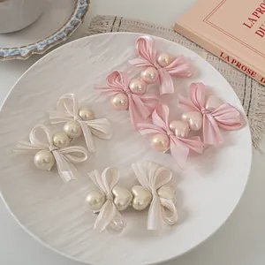Detailed set of four satin bow hair clips with pearls and hearts in a ceramic plate