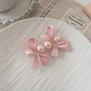 Detailed macro view of pink silk ribbon bows and soft faux pearls on a vintage hair clip