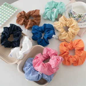 Detailed close-up of colorful scrunchies with fabric labels in a minimalist gift box