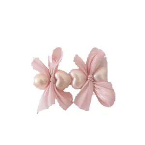 Set of two light pink silk bow hair clips with heart-shaped faux pearl decorations