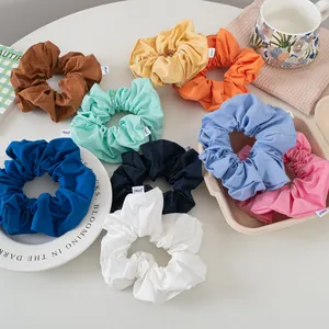 Flat lay of colorful cotton scrunchies set with woven labels on a white desktop