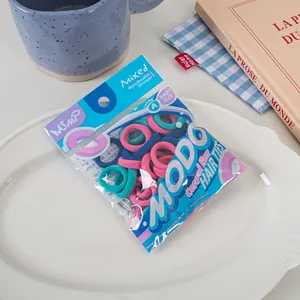 Detail view of colorful baby-sized hair ties in branded transparent bag packaging