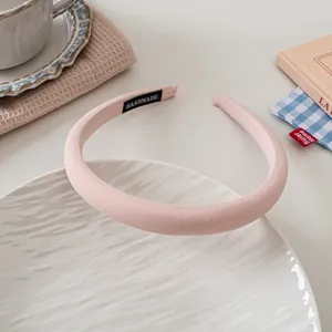Detail of pink padded sponge headband with handmade label on white ceramic plate