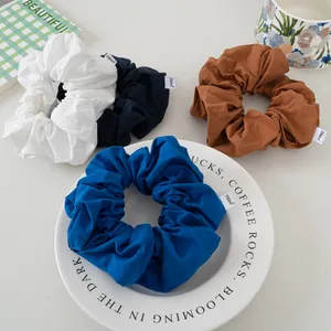 Set of four colorful fabric scrunchies with labels in white, black, brown and blue
