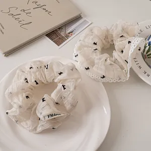 Set of two cream white mesh hair scrunchies with black bird patterns and lace trim