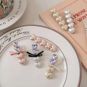 Eleganti fermagli per capelli con cuori di perle e fiocchi di strass in vari colori su piatto