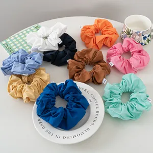 Close-up of nine colorful scrunchies with labels on a white table and plate