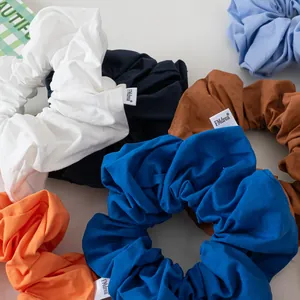 Flat lay close-up of colorful cotton hair scrunchies with minimalist woven fabric labels