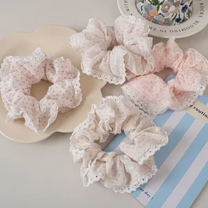 Detailed view of four pastel polka dot scrunchies with white lace edges on a tray