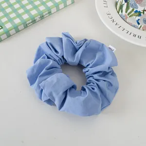 Detail of light blue oversized scrunchie with soft fabric texture and woven brand label