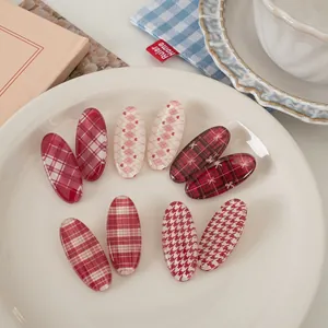 Detailed set of red plaid and houndstooth hair clips displayed on a white plate