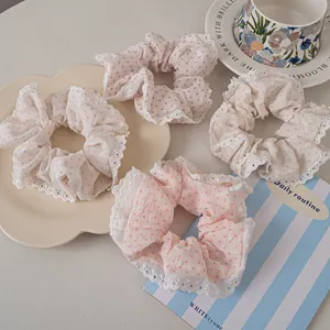 Close-up of four lace-edged polka dot scrunchies in pastel colors on a vintage tray