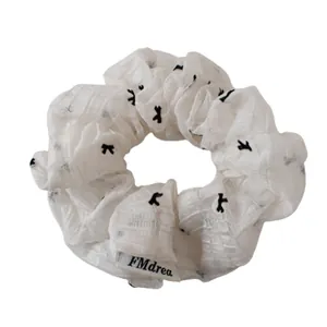 White lace mesh scrunchie with black print and brand tag for elegant summer hairstyles