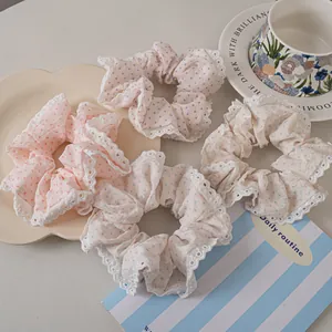 Close-up of four lace-trimmed polka dot hair scrunchies in pastel pink, purple, blue and green