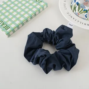 Detailed view of dark blue fabric scrunchie with a white brand label on a stylish table