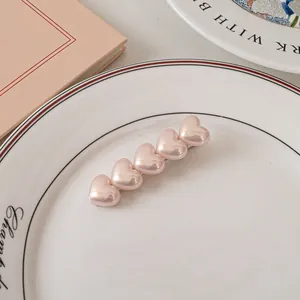 Dettaglio dei fermagli per capelli a cuore rosa perlato su un piatto di ceramica bianca